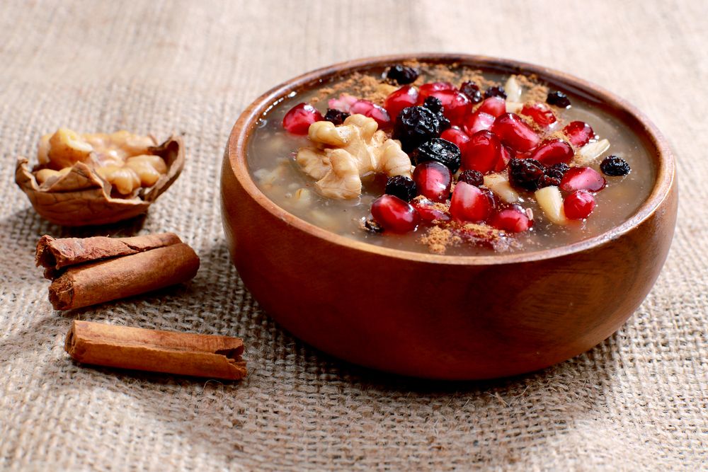 A delicious bowl of Asure, topped with nuts and pomegranate seeds.