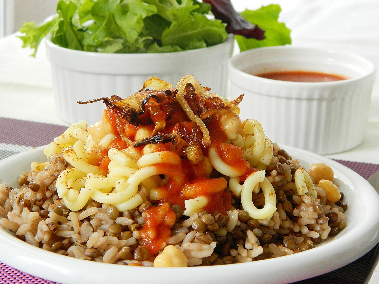 A delicious serving of Koshary, featuring rice, lentils, pasta, and tomato sauce