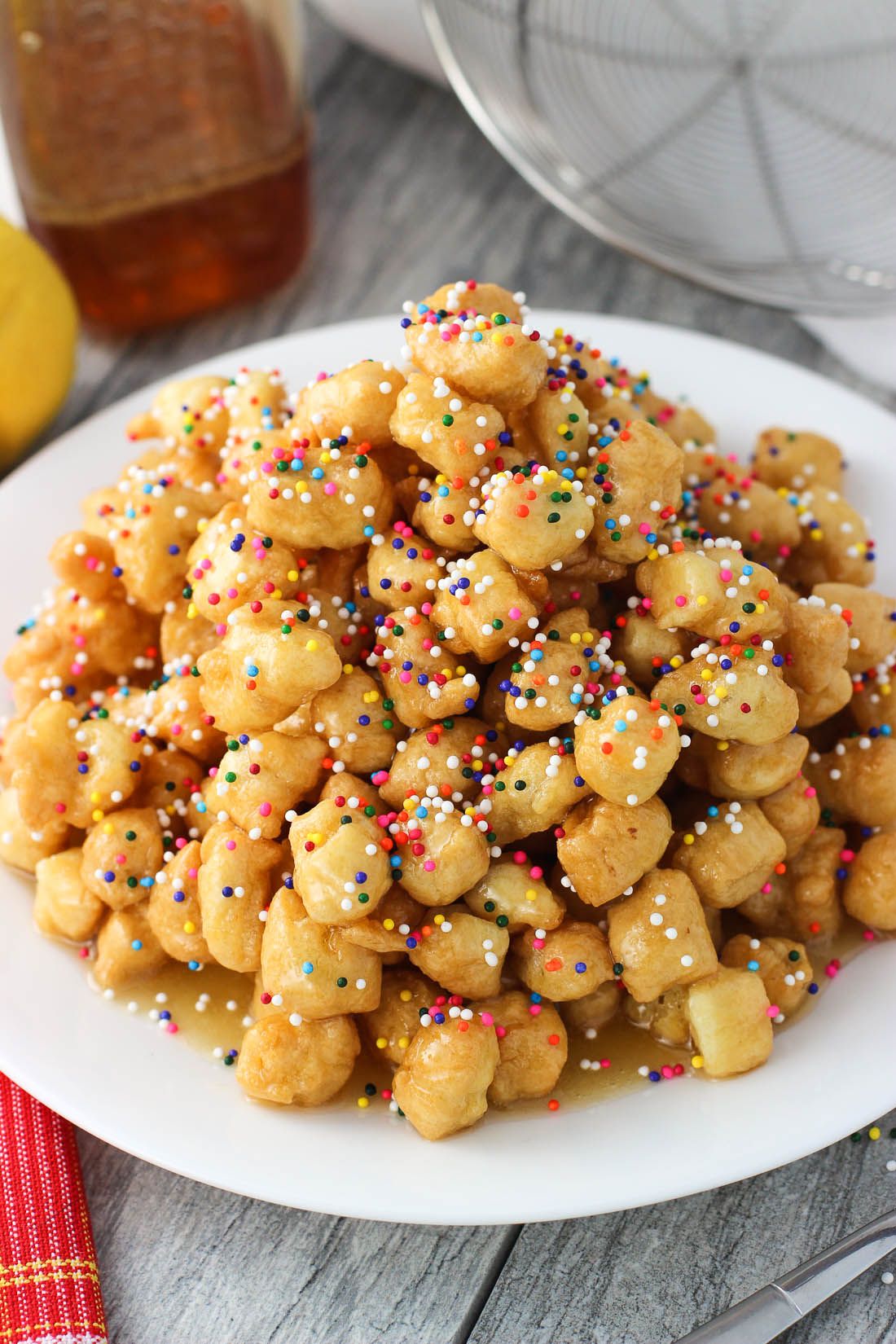 A beautiful plate of Struffoli drizzled with honey and topped with colorful sprinkles