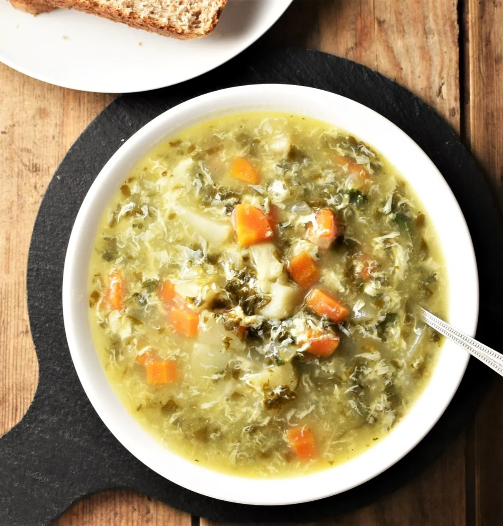 A bowl of sorrel soup garnished with fresh herbs and cream