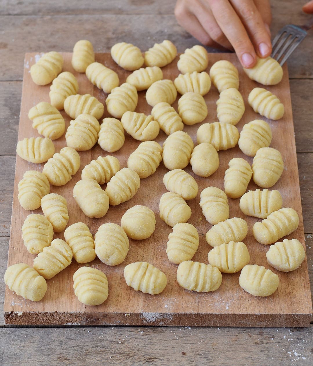 Homemade gluten-free vegan gnocchi before cooking on a cutting board.