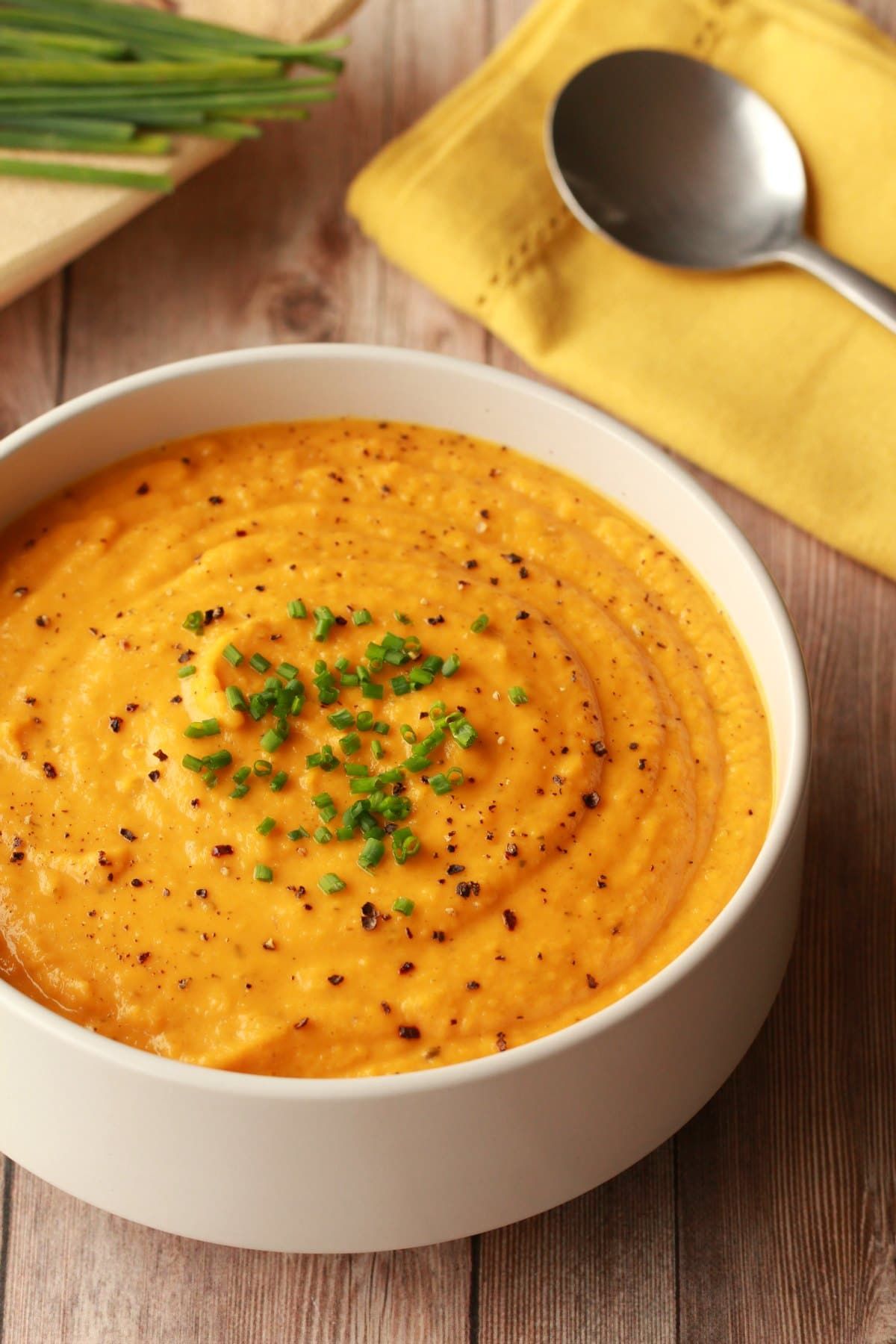 A bowl of rich and creamy roasted butternut squash soup garnished with herbs