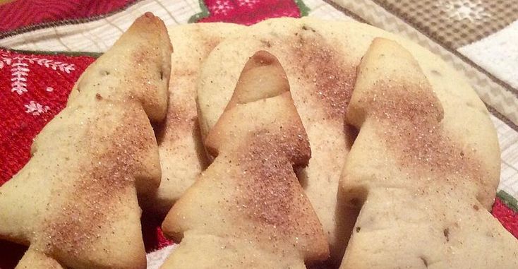 Some food is laying out on a red and green table cloth with snowflakes